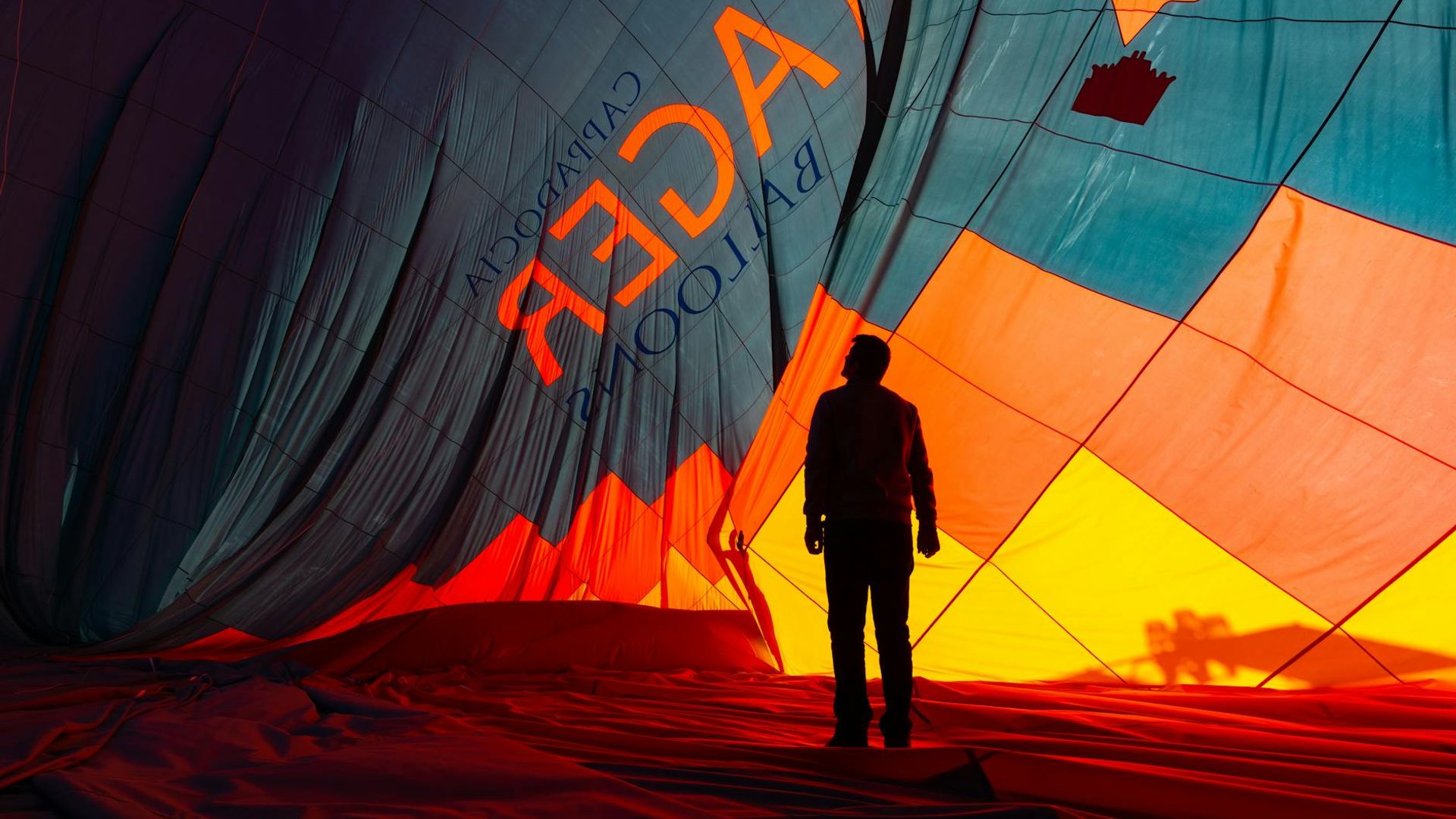 Silhouette of a person stretching during sunrise with orange glow.